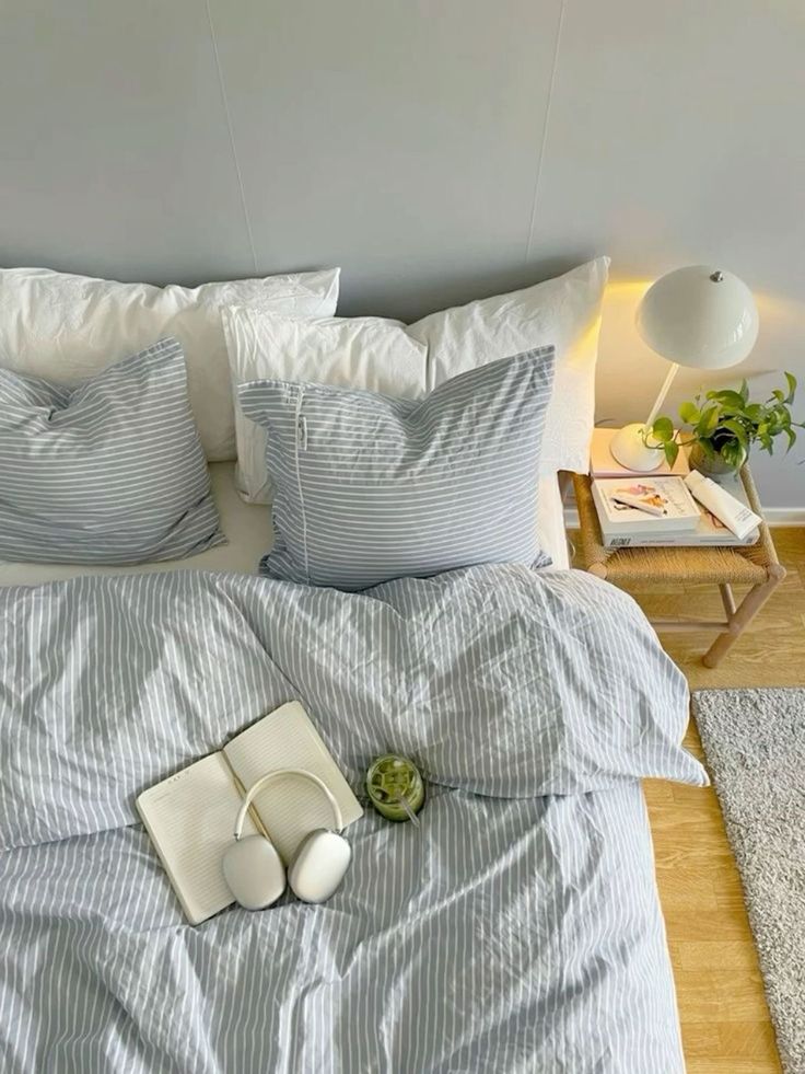 a bed with blue and white striped sheets, pillows and pillow cases on top of it