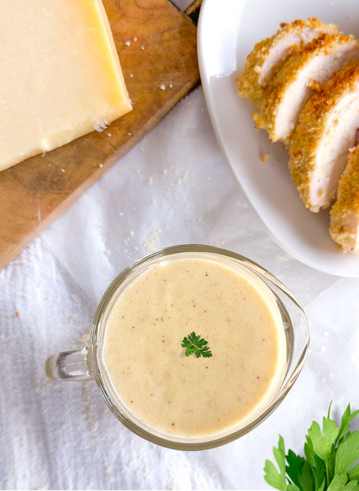 a glass cup filled with liquid next to sliced cheese