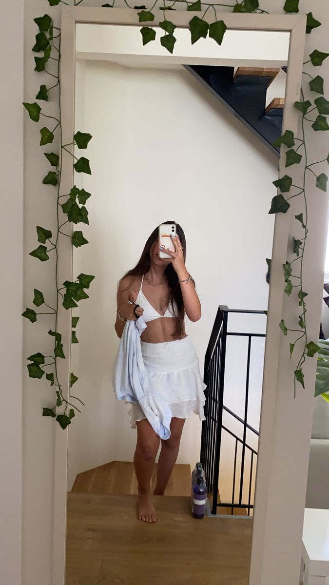 a woman taking a selfie in front of a mirror with ivy growing on it