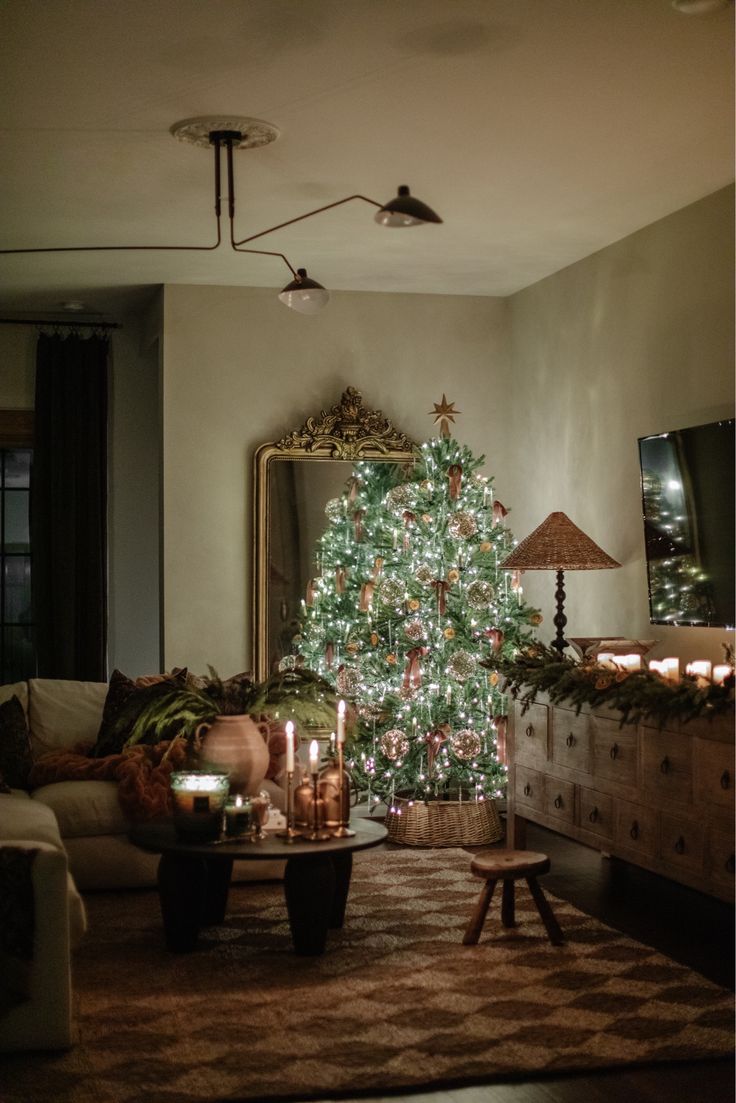 a living room with a lit christmas tree in the corner and candles on the coffee table