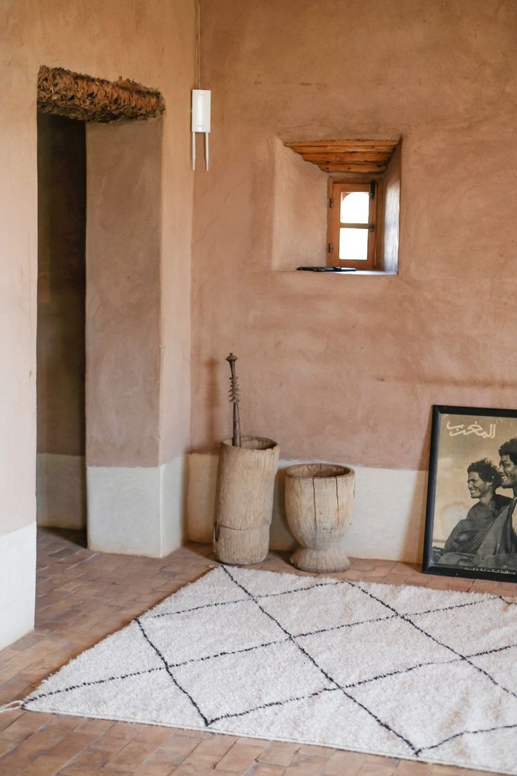 a room with a rug, window and potted plant on the floor