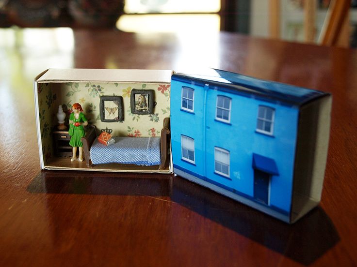 an open dollhouse with a bed in it on a wooden table next to a doll house