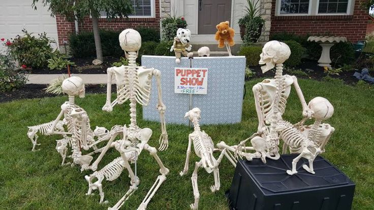 a group of skeleton figurines sitting on top of a green field next to a box