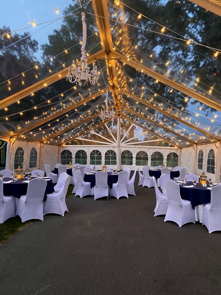 the inside of a tent with tables and chairs set up for a wedding or party