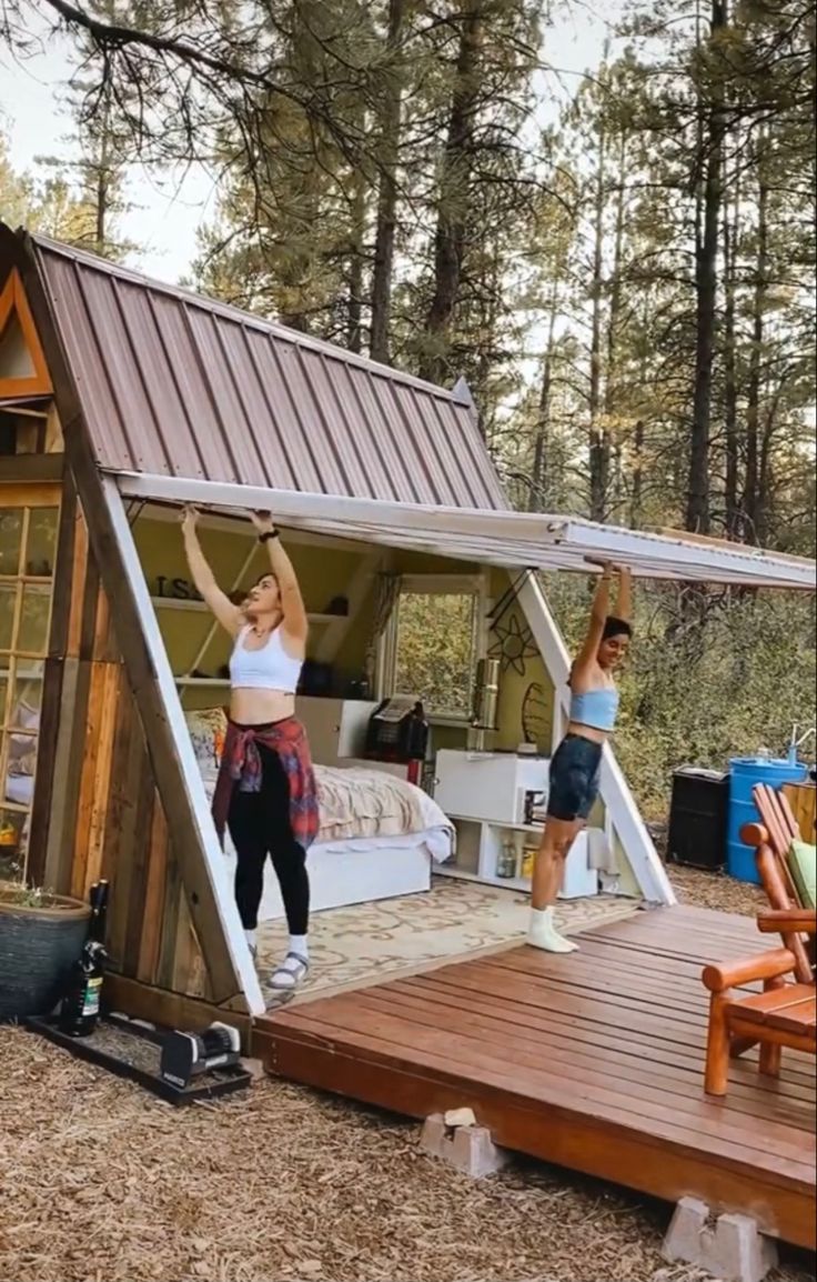 two women are doing yoga in front of a tiny house with a roof that has been built into the ground