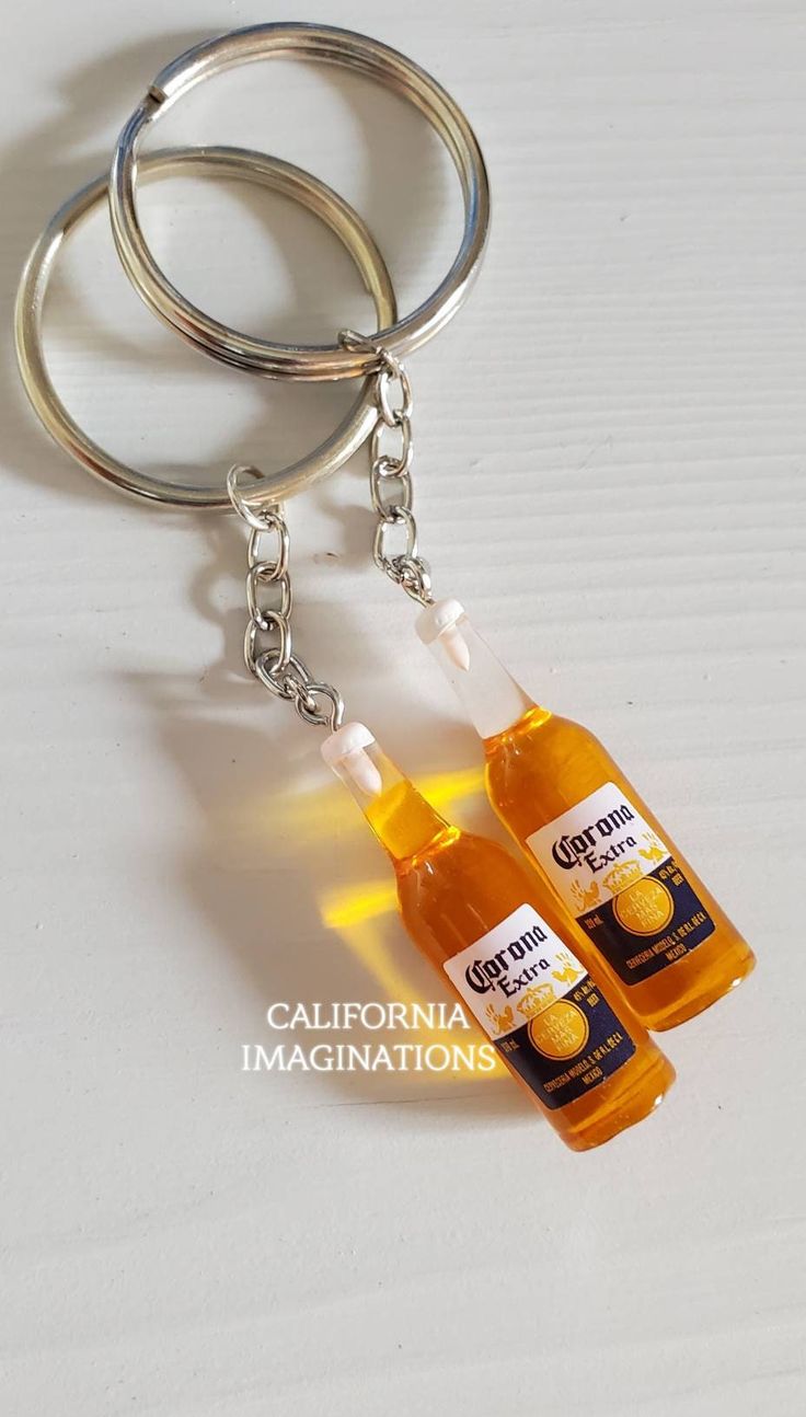 two bottles of orange juice sitting on top of a keychain that is attached to a pair of metal rings