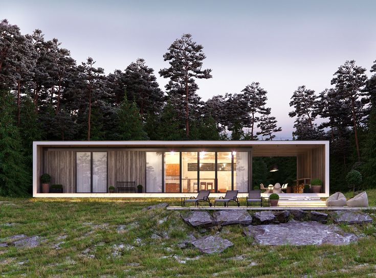 a house in the middle of a forest with grass and rocks on the ground next to it