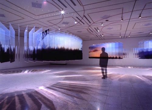 a man is standing in an empty room with large paintings on the walls and floor