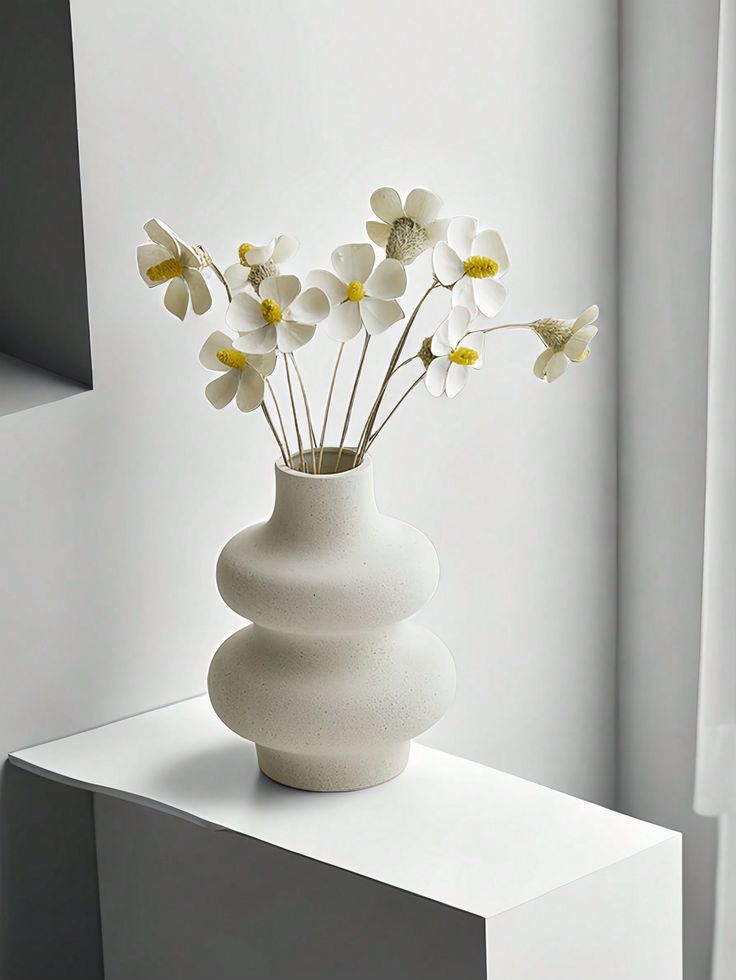 a white vase with some flowers in it