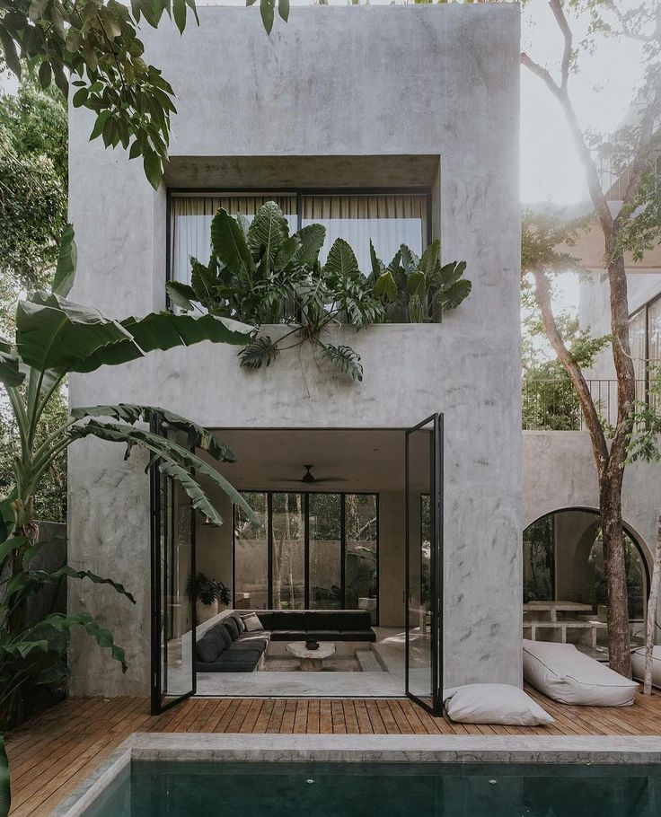 a house with a pool surrounded by greenery and plants on the outside wall is shown