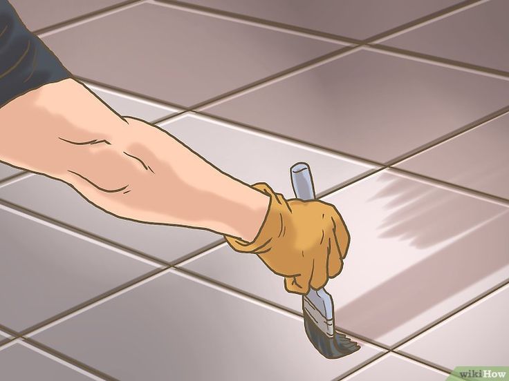 a tile floor being cleaned by a person with gloves on and holding a brush in their hand