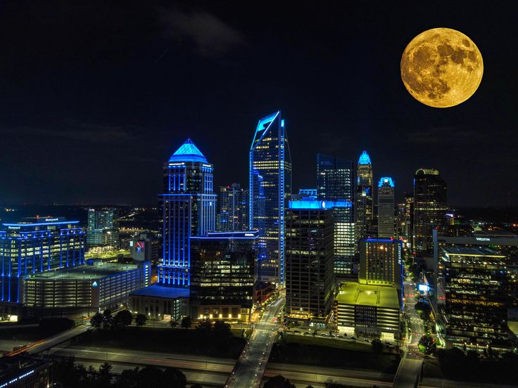 a full moon is seen over the city skyline