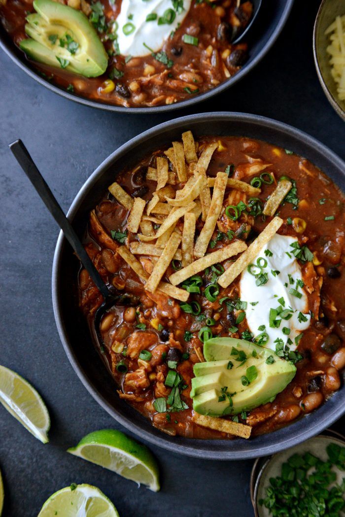 three bowls filled with chili, beans and avocado on top of a table