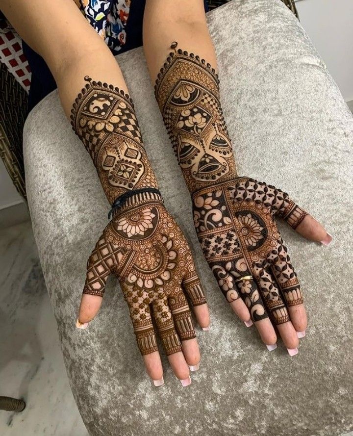 two hands with henna tattoos on them, one is showing off the intricate design