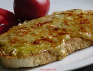 there is a piece of bread with cheese on it and some tomatoes next to it