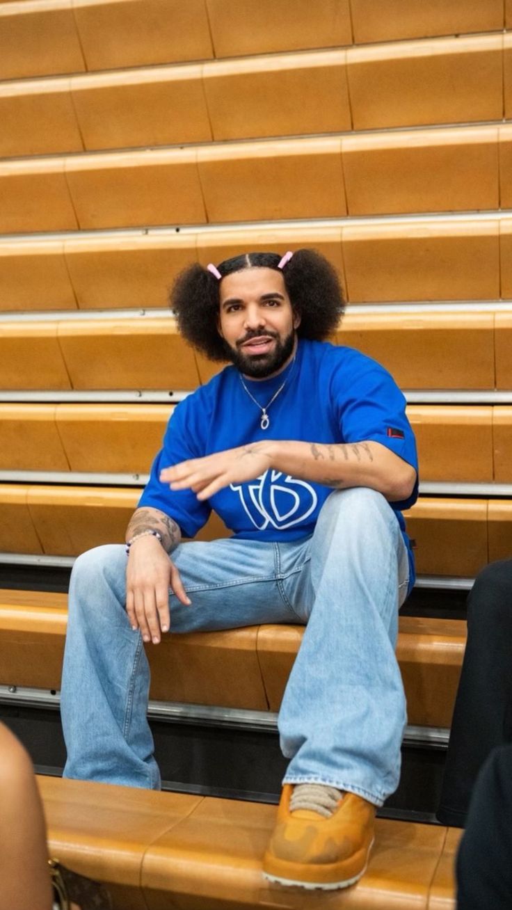 a man sitting on top of a wooden bench in front of a row of bleachers