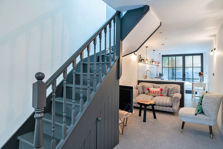 a living room filled with furniture next to a stair case