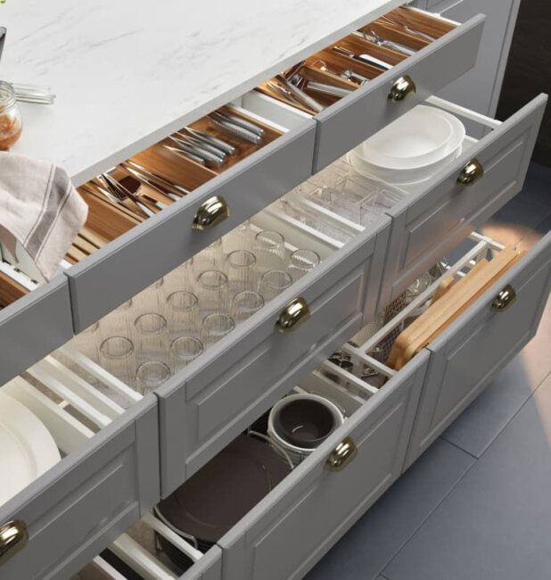 an open drawer in a kitchen filled with dishes and utensils on the counter