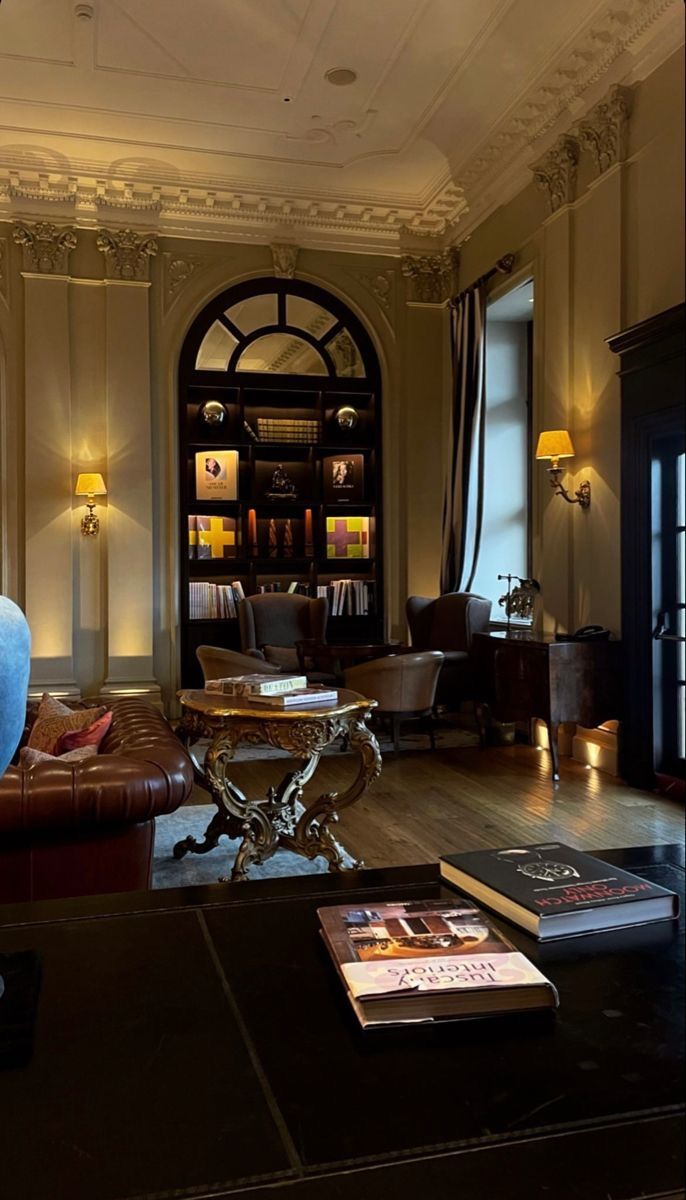 a living room filled with lots of furniture and books on top of a wooden floor