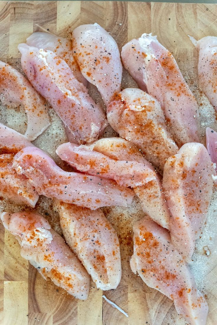 raw chicken pieces on a cutting board with seasoning sprinkled around the edges