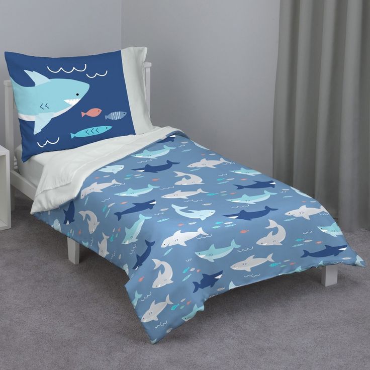 a child's bed with a shark comforter and matching pillowcase in blue