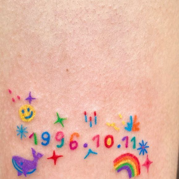 a woman's thigh with colorful tattoos and numbers on the side of her leg