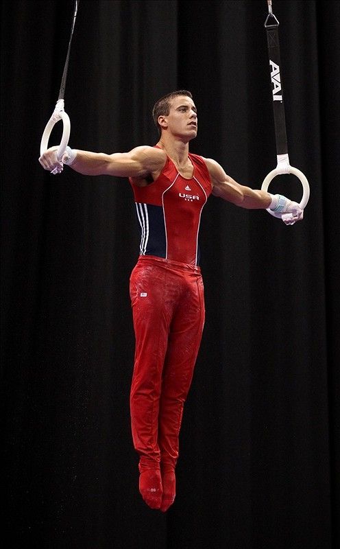 a man is performing on the rings with his hands