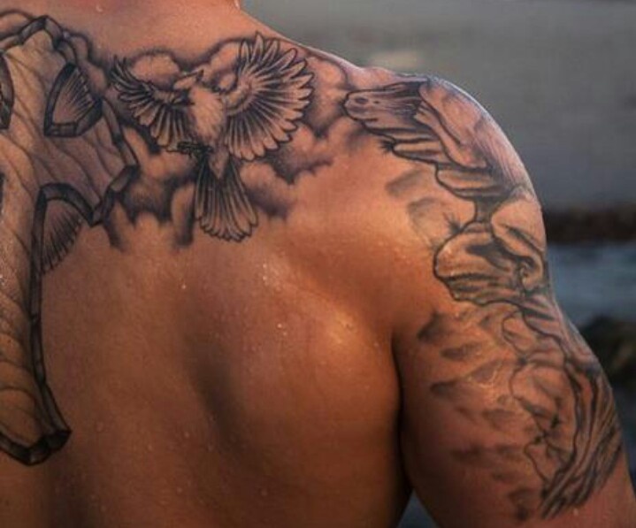 the back of a man's shoulder with flowers and birds tattoo on his upper half