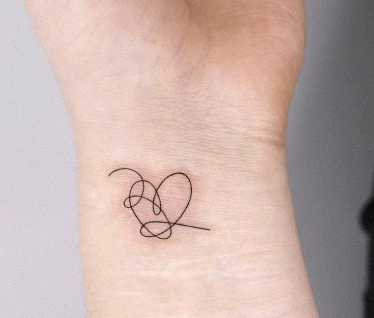 a small tattoo on the wrist of a woman's left arm with two intertwined circles