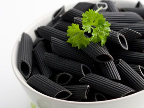 black pasta with parsley in a white bowl