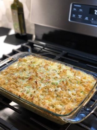 a casserole dish sitting on top of an oven with a bottle in the background