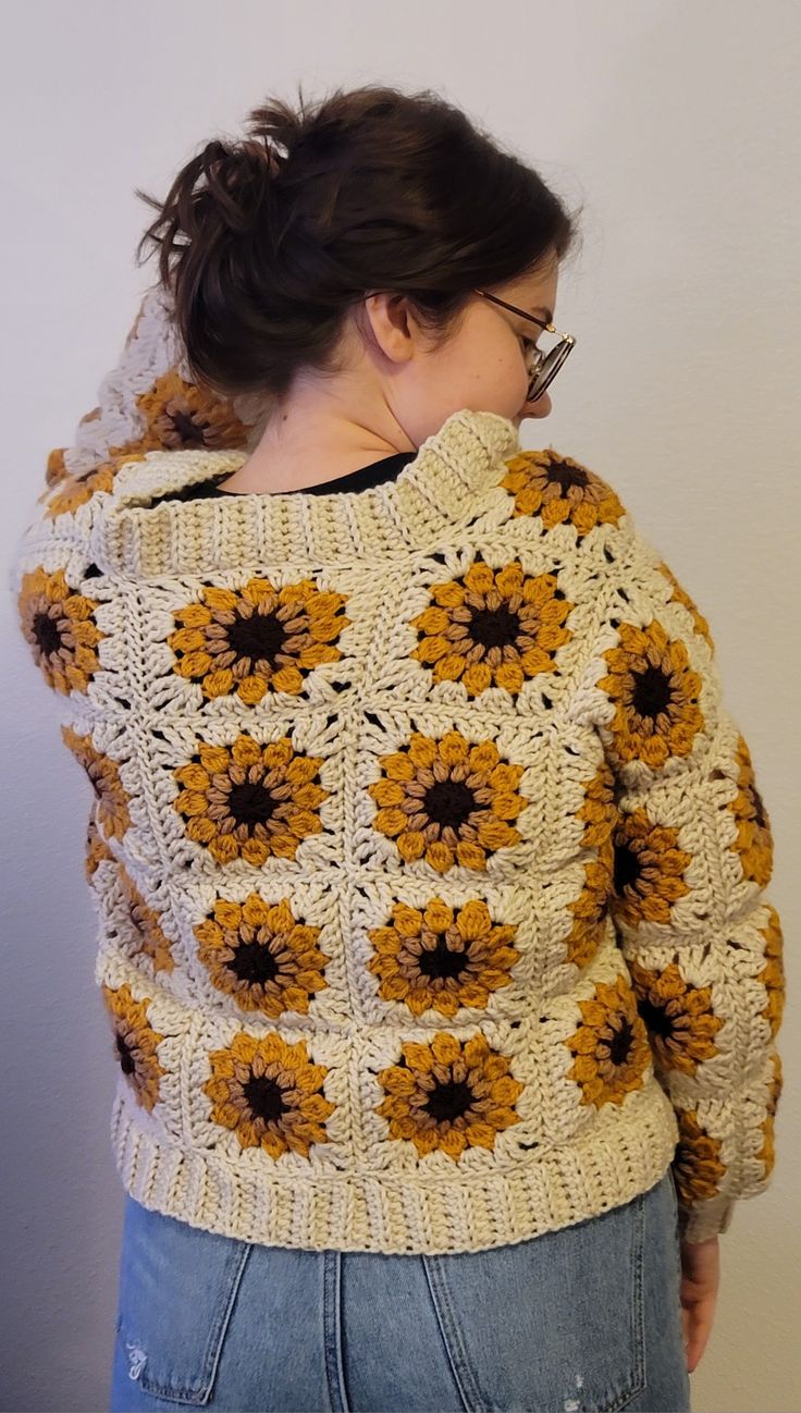 a woman is wearing a crocheted sweater with sunflowers on it