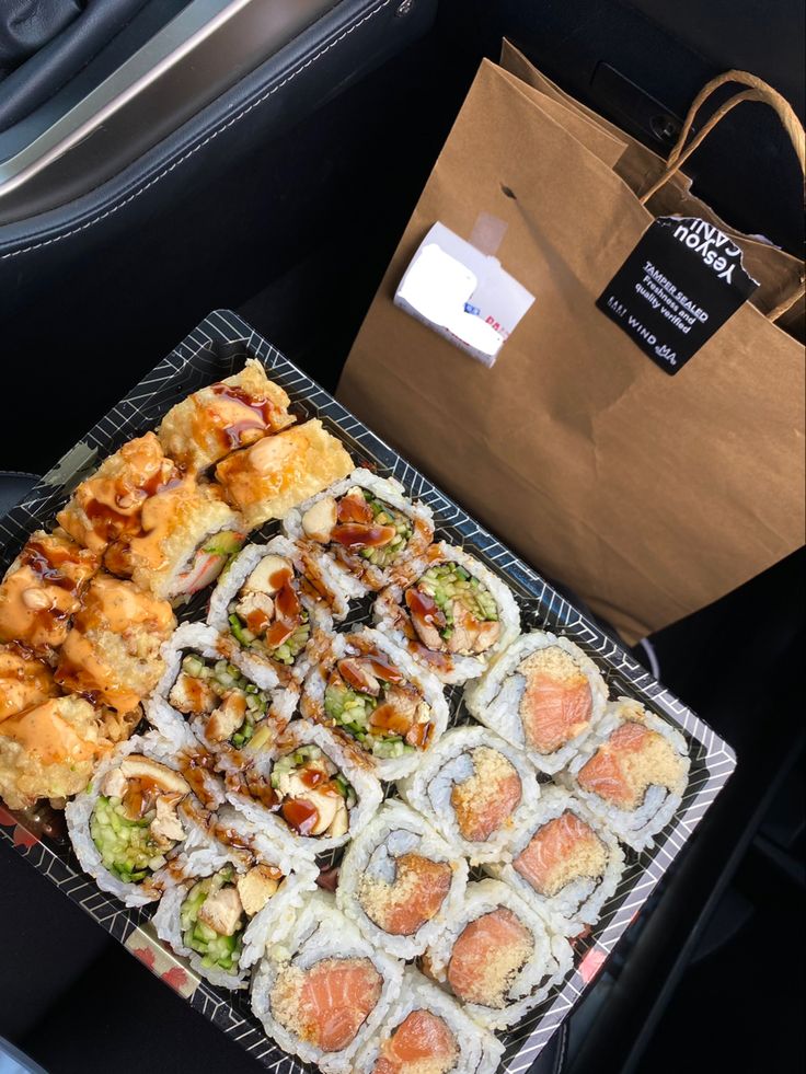 sushi and rolls are sitting on a tray in the back seat of a car