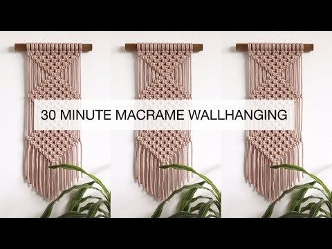 three pink macrame wall hangings on a white wall with bamboo plant in front