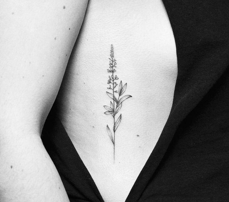 a black and white photo of a woman's stomach with a flower tattoo on it