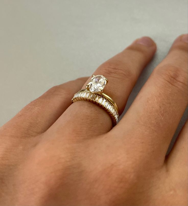 a person's hand with two rings on their fingers and one is wearing a diamond ring