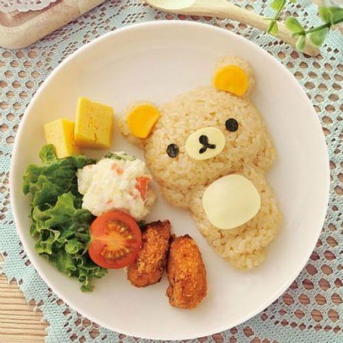 a white plate topped with rice and veggies next to a teddy bear face