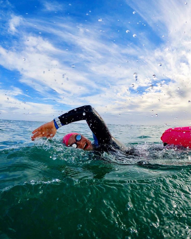 a man swimming in the ocean on top of a surfboard