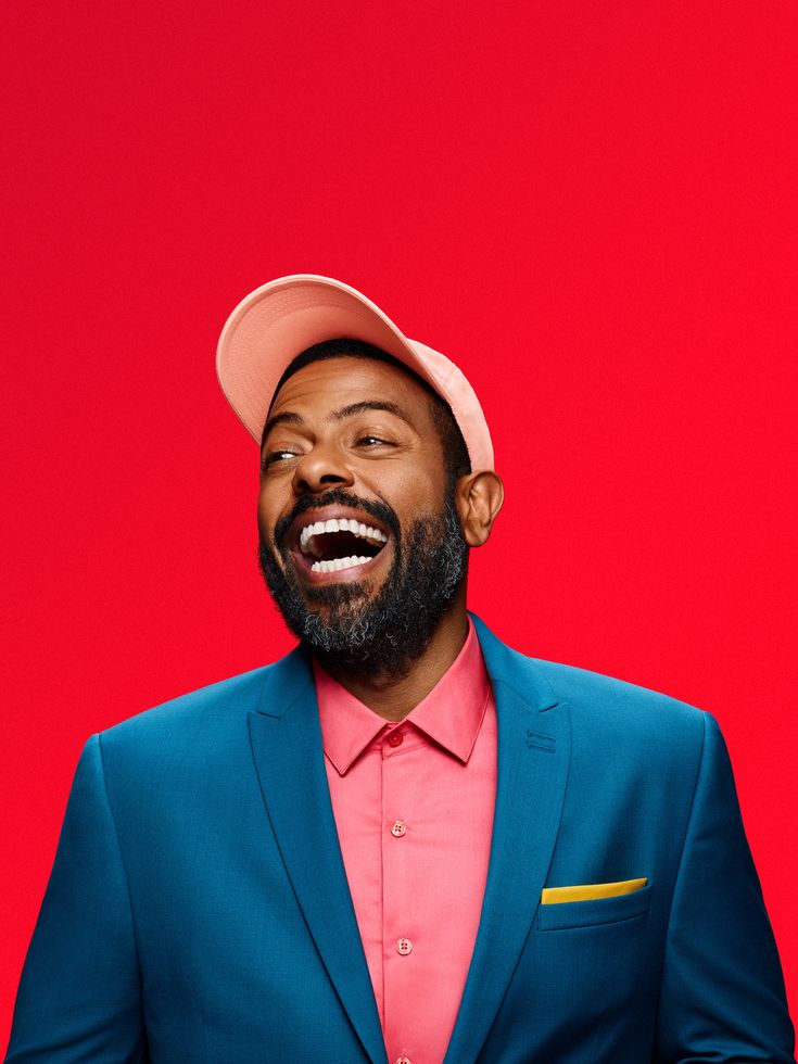 a man in a blue suit and pink shirt with a red hat on his head