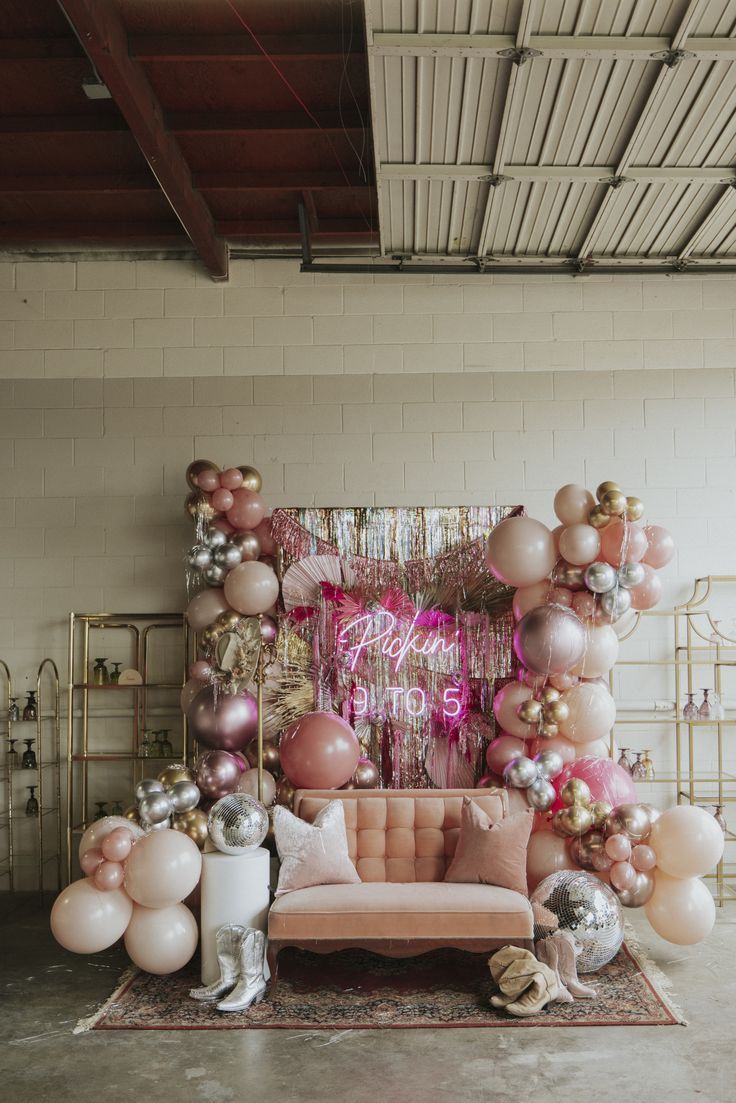 a living room filled with balloons and couches in front of a white brick wall