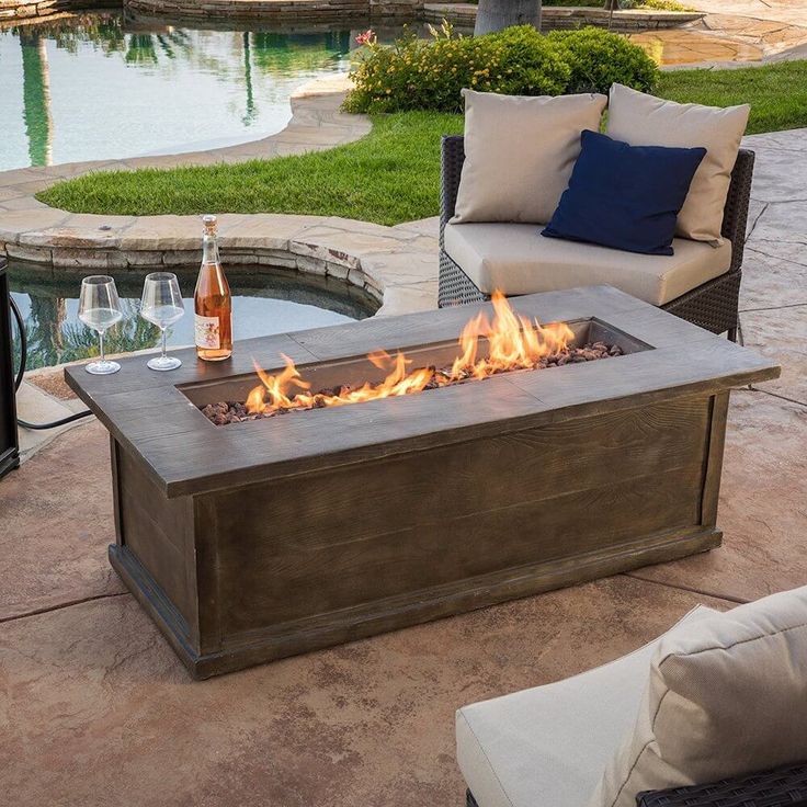 a fire pit sitting on top of a patio next to a swimming pool