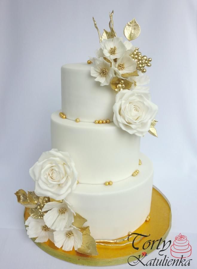 a wedding cake with white flowers and gold decorations