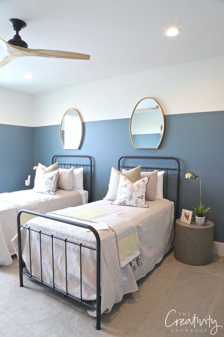 two twin beds in a bedroom with blue walls and white bed linens on them