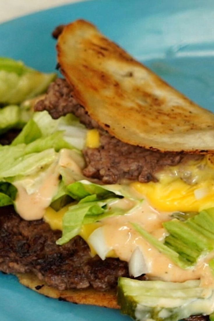 a sandwich with lettuce, cheese and meat on it sitting on a blue plate