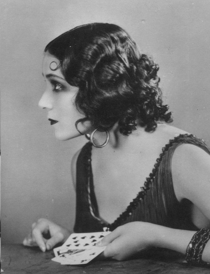 an old black and white photo of a woman with large hoop earrings on her head