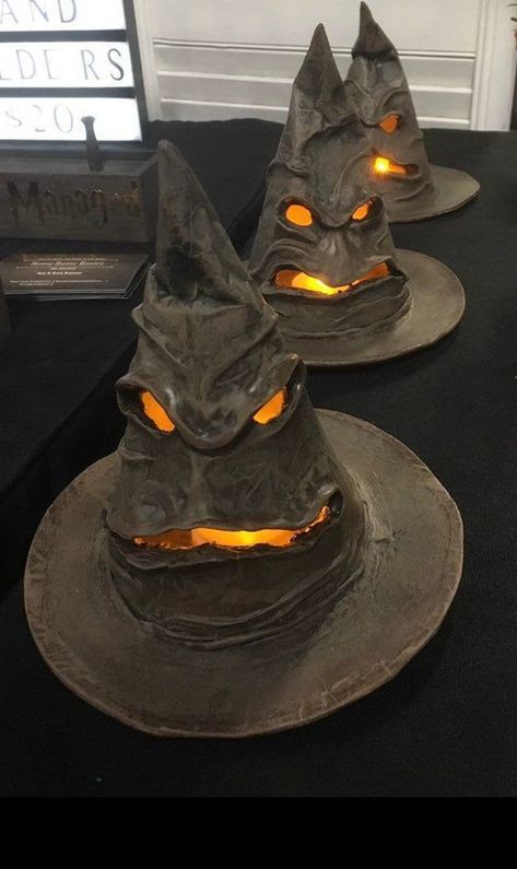 three halloween hats with glowing eyes on them sitting on a black tablecloth covered table