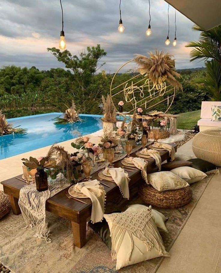 an outdoor dining area next to a swimming pool with lots of pillows and blankets on it