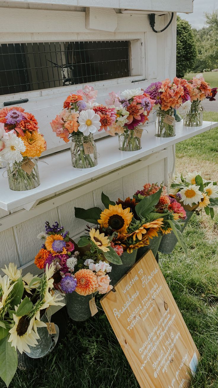 sunflowers and other flowers are arranged in vases on the side of a building