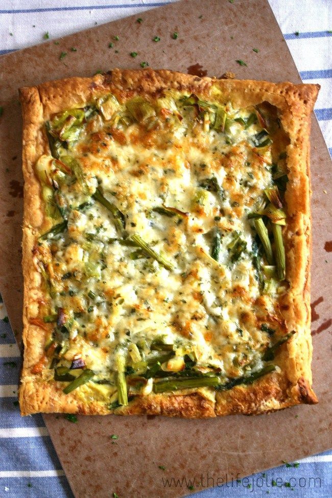 a square vegetable quiche with cheese and asparagus on a piece of parchment paper