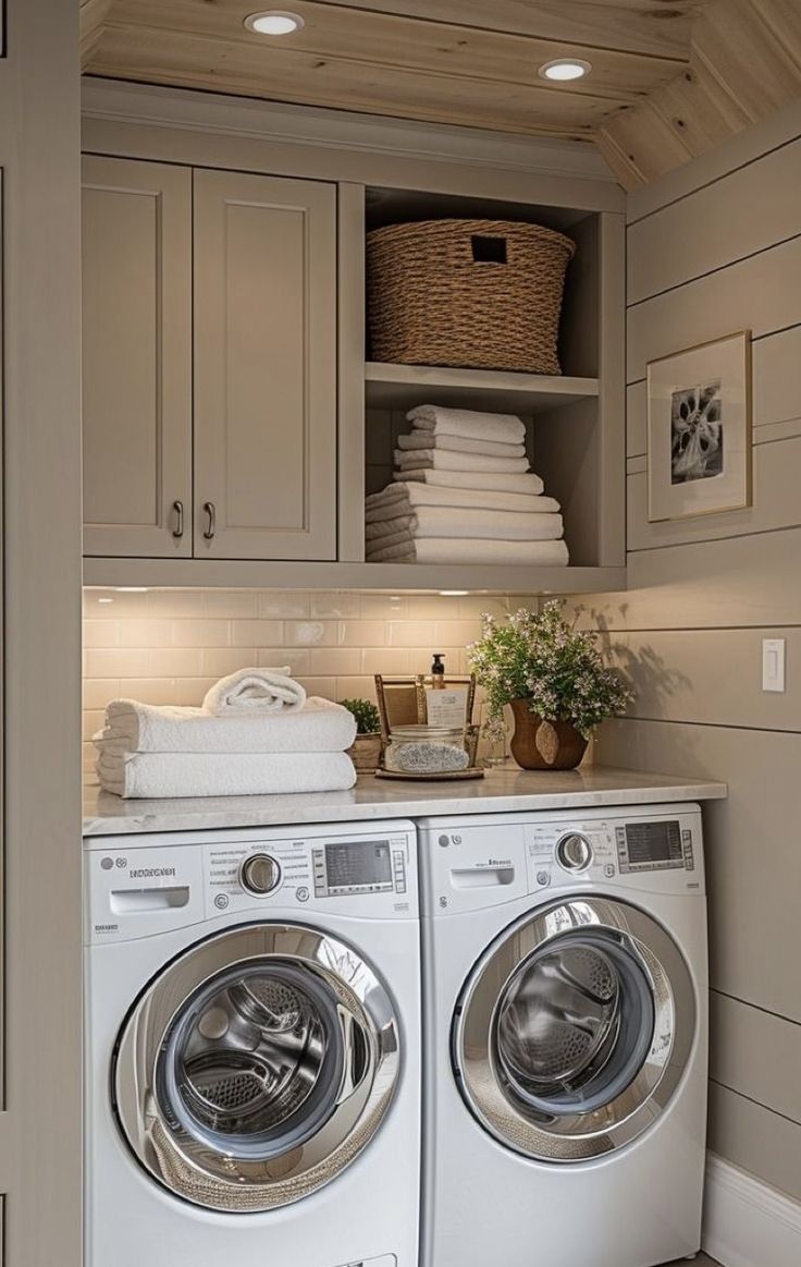 a washer and dryer in a laundry room with cabinets on the wall above them